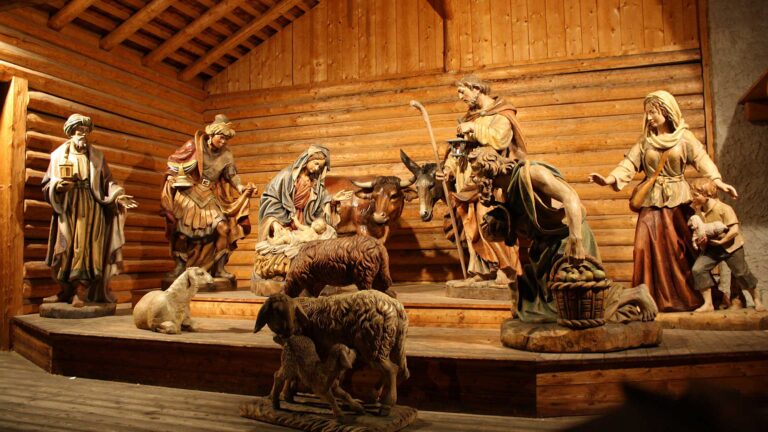 Presepe artistico in legno con la Natività, statue a grandezza naturale in una scenografia rustica.