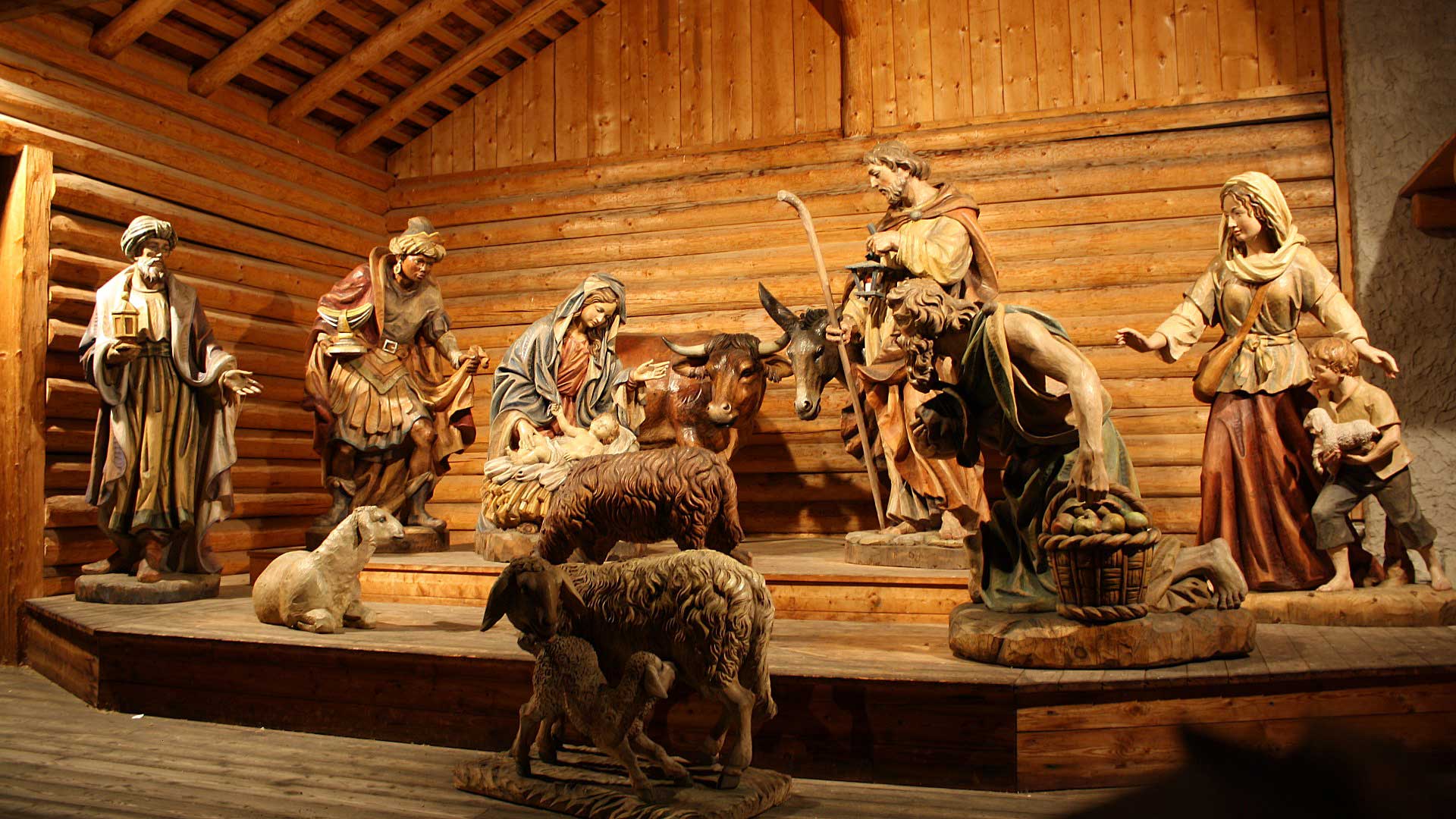 Presepe artistico in legno con la Natività, statue a grandezza naturale in una scenografia rustica.